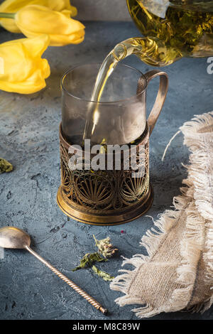 Versando il tè in tazza mug di teiera con detox drink da menta peperita bollito di acqua calda scende la condensa salirà di vapore sulla pietra grigia Concetto di sfondo Foto Stock