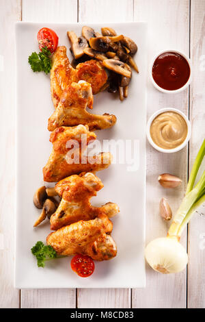 Grigliata di ali di pollo su un tavolo di legno Foto Stock