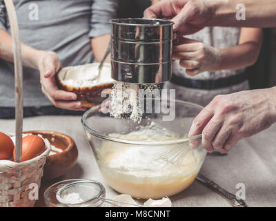 Le madri e i bambini con le mani in mano cuocere la pasta per biscotti fatti in casa. Abbiamo cuoco in cucina insieme con i bambini. Famiglia felice Foto Stock