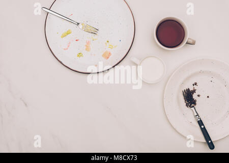 Vista superiore delle piastre disposte con pezzi di dolci e bevande sul piano portapaziente bianco Foto Stock