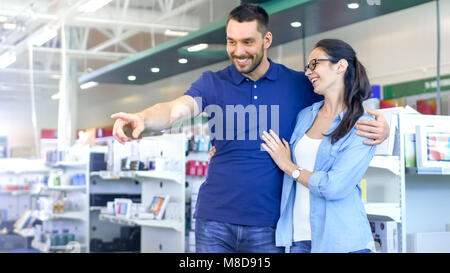 Nel negozio di elettronica Bella coppia Giovane sono alla ricerca di un nuovo dispositivo elettrico. Gli uomini punta il dito a qualcosa. Store è grande e moderno. Foto Stock