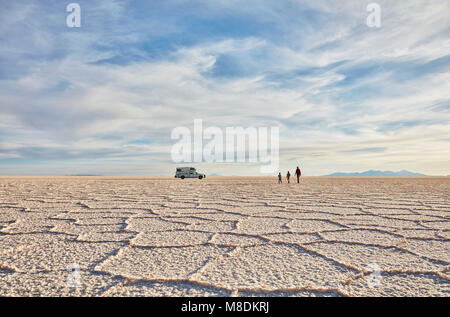 Madre e figli a piedi attraverso le saline, veicolo per attività ricreative in background, Salar de Uyuni, Bolivia Foto Stock