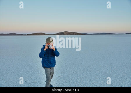 Giovane ragazzo in piedi sul saline, guardando attraverso la telecamera, Salar de Uyuni, Uyuni, Oruro, Bolivia, Sud America Foto Stock