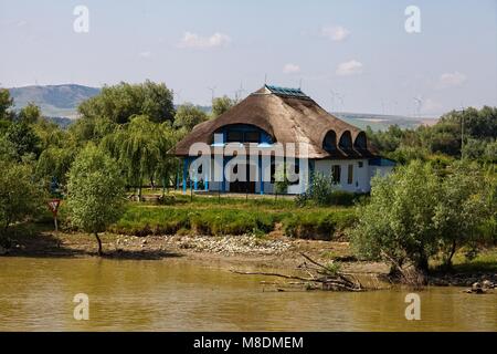 Le spalliere tetto di paglia e delle turbine a vento A VALLE DI TULCEA sul fiume Danubio DELTA Foto Stock