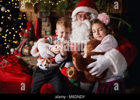 Giovane ragazza e ragazzo visitare Santa, tenendo doni Foto Stock