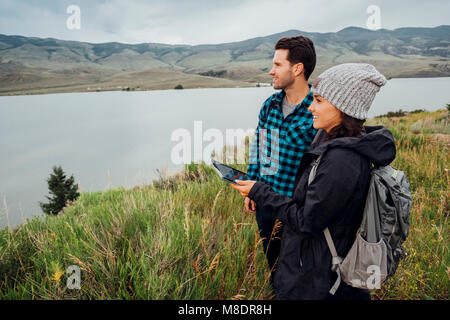 Escursionismo coppia, in piedi accanto al serbatoio di Dillon, giovane donna azienda digitale compressa, Silverthorne, Colorado, STATI UNITI D'AMERICA Foto Stock