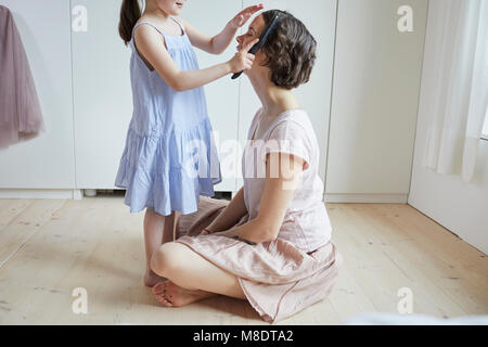 Madre seduta sul pavimento, figlia di madre di spazzolatura dei capelli, metà sezione Foto Stock