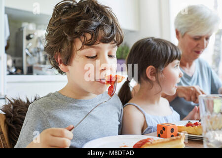 Ragazzo di mangiare il pranzo a tavola con la sorella e la nonna Foto Stock