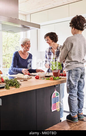 Ragazzo giovane madre e nonna rendendo la pizza insieme in cucina Foto Stock