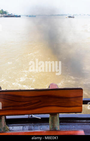 Denso fumo nero si riversa dal retro di una imbarcazione turistica sul fiume Meekong, Vietnam Foto Stock