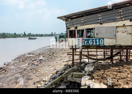 Una corsa verso il basso casa costruita su palafitte sulla banca del fiume Meekong, Vietnam Foto Stock
