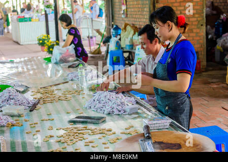 La gente forma dolci fatti da noci di cocco a mano prima del confezionamento e imballaggio, Vietnam Foto Stock