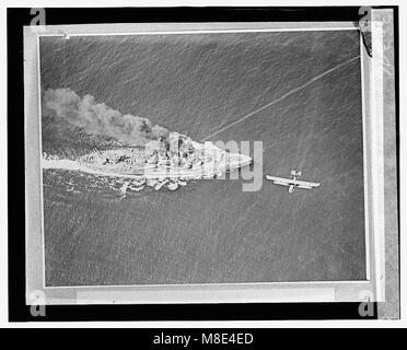 Questa fotografia cattura la scia di un siluro che colpisce la USS Oklahoma (in seguito attraversata e sostituita dall'Arkansas) durante un'esercitazione navale. L'immagine presenta anche un aereo che passa davanti alla nave, probabilmente documentando l'evento. Foto Stock