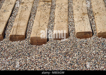 Sentiero in legno sulla spiaggia di ciottoli per una comoda passeggiata fino all'acqua estrema closeup Foto Stock