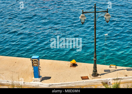 Bitt ormeggio giallo situato vicino al semaforo su un fondo di cemento vuoto a mare blu con piccole onde in estate giorno di sole Foto Stock