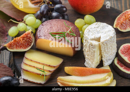 Set di ottimi formaggi con frutta e miele. Camembert. Bree. Uva, fichi, pere e rosmarino. Vino snack per foodies. Messa a fuoco selettiva Foto Stock