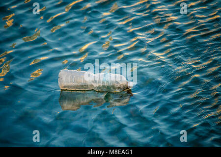 Floating bottiglia di plastica in acqua di ondulazione Foto Stock