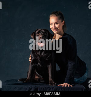 La giovane donna che abbraccia un mix di cane di razza Foto Stock