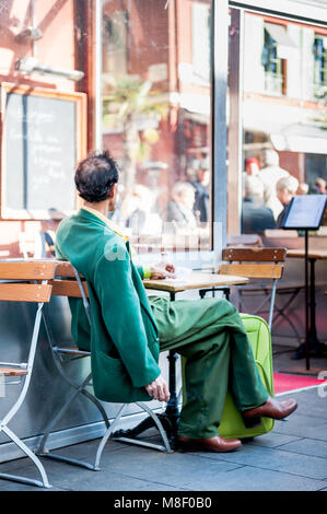 Molto elegante gentleman indossando un recupero verde corrispondente ensemble si rilassa in vecchio stile cafe a Nizza Francia in inverno. Foto Stock