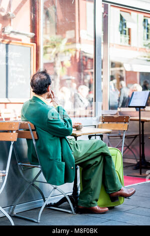 Molto elegante gentleman indossando un recupero verde corrispondente ensemble si rilassa in vecchio stile cafe a Nizza Francia in inverno. Foto Stock