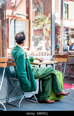 Molto elegante gentleman indossando un recupero verde corrispondente ensemble si rilassa in vecchio stile cafe a Nizza Francia in inverno. Foto Stock