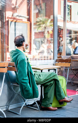 Molto elegante gentleman indossando un recupero verde corrispondente ensemble si rilassa in vecchio stile cafe a Nizza Francia in inverno. Foto Stock