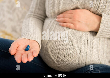 Donna incinta azienda pillole in mano Foto Stock