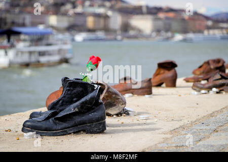 Un solitario fiore è a sinistra al Memorial Sculpture 'i pattini sul Danubio Promenade", in ricordo degli ebrei ungheresi che sono stati eseguiti. Foto Stock