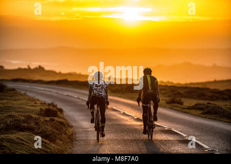 Due ciclisti su strada sulla strada passato Haytor su Dartmoor nel Devon a sunrise. Foto Stock