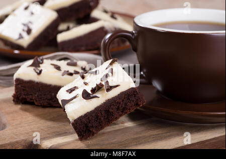 Primo piano di due strati di cioccolato brownies con una tazza di caffè su un vassoio in legno Foto Stock