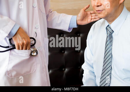 Bello medico sta esaminando il paziente di sesso maschile è ferito al collo e dando una consultazione per il suo paziente Foto Stock