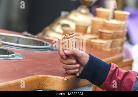 La mano di un bambino tiene un vuoto di cono gelato Foto Stock