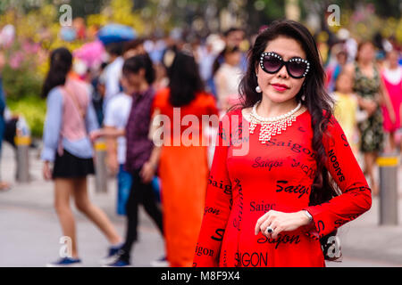 Il Vietnam una donna che indossa un abito rosso dicendo "aigon' più volte e un paio di occhiali da sole Gucci, Ho Chi Minh City, Vietnam Foto Stock