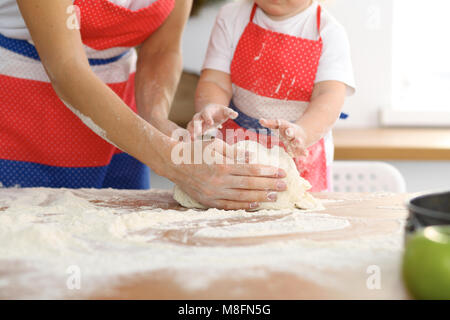 Sua madre e la sua figlia carino mani prepara la pasta su un tavolo di legno. Dolci fatti in casa per il pane o pizza. Sfondo di panetteria Foto Stock