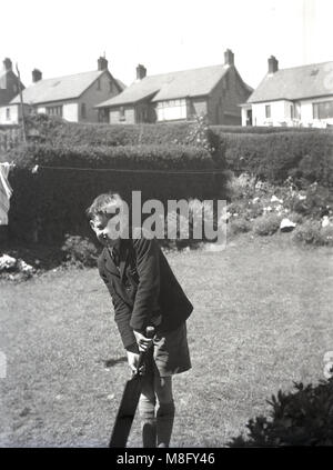 1950, storico, estate e al di fuori di un suburban giardino sul retro, uno scolaro in giacca e pantaloni corti con una vecchia cricket bat, Inghilterra, Regno Unito. Foto Stock