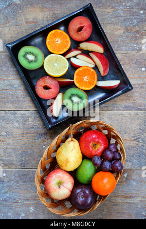 E tutta la frutta a fette di mele, calce, limone, pere e prugne su tavola in legno rustico - verticale in modalità verticale Foto Stock