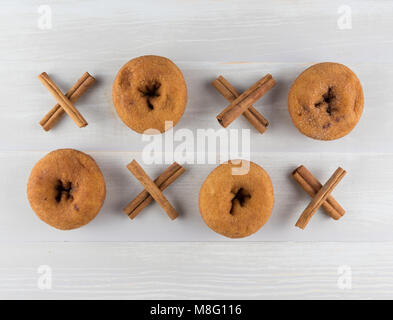 Griglia di cannella Xs e ciambella Os su luce tavolo in legno Foto Stock