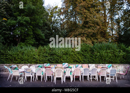 Lungo tavolo e sedie con imbottitura misto al di fuori sul cortile in attesa per un gruppo di amici in vacanza per popolarli. Concetto di team building, amicizia o stare insieme. Foto Stock