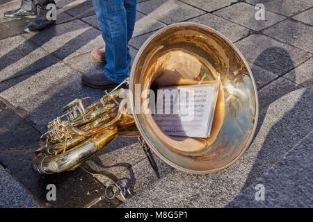 Close-up di una bella e luminosa tuba in appoggio sul pavimento con il punteggio della canzone "Siamo in parti" nella piazza di Zocodover, Spagna Foto Stock