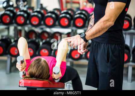 Giovane donna treni tricipiti con trainer in palestra Foto Stock