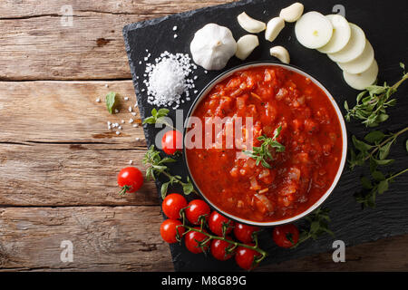 Italiano salsa pizzaiola con pomodori, origano e aglio e cipolla vicino sul tavolo. parte superiore orizzontale vista da sopra Foto Stock
