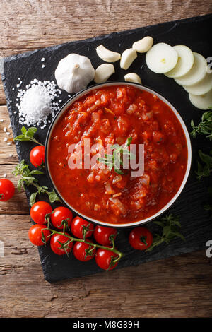 Italiano salsa pizzaiola con pomodori, origano e aglio e cipolla vicino sul tavolo. Verticale in alto vista da sopra Foto Stock