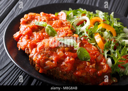 Italiano di carne alla pizzaiola carne e verdura fresca insalata di close-up su una piastra sul tavolo orizzontale. Foto Stock