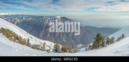 Vista di un altopiano di montagna, ricoperta di neve, guardando a sud della valle. Nevato picchi distanti all'orizzonte. Il silenzio della foresta d'inverno. Foto Stock