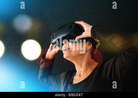 Una donna anziana in realtà virtuale occhiali. Una persona anziana utilizzando la tecnologia moderna. Foto Stock