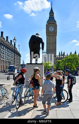 Gruppo di turisti in bicicletta & tour guida accanto a nolo bici riuniti intorno a statua di Sir Winston Churchill in piazza del Parlamento Big Ben Londra Inghilterra REGNO UNITO Foto Stock