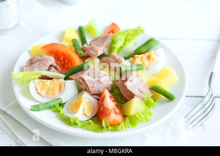 Insalata Nizzarda con tonno, uova, patate e fagioli verdi e pomodori. Tradizionale Insalata Nicoise blu su sfondo di legno, vista dall'alto, copia dello spazio. Foto Stock