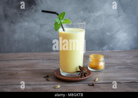 Curcuma Lassie o lassi in vetro - sani indiano probiotici bevanda fredda fatta di cagliata (yogurt), latte, spezie e zucchero. Curcuma Smoothie su legno, Foto Stock