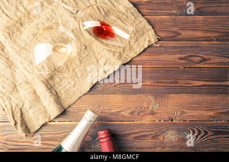 Foto di due bottiglie di vino e bicchieri di vino sul tovagliolo sulla brown, sullo sfondo di legno. Foto Stock