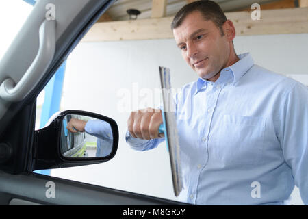 Giovane uomo pulito con cura la sua macchina windows Foto Stock